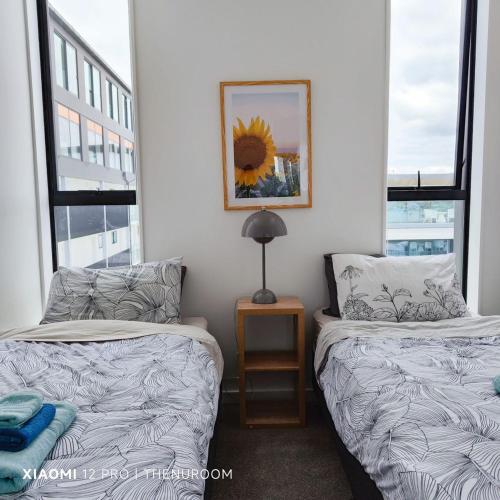 two beds in a room with two windows at Auckland Birkenhead BNB in Auckland