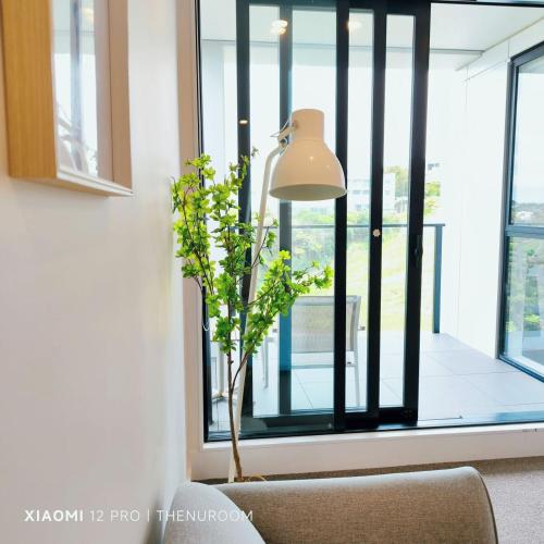 a lamp and a plant in a room with a window at Auckland Birkenhead BNB in Auckland
