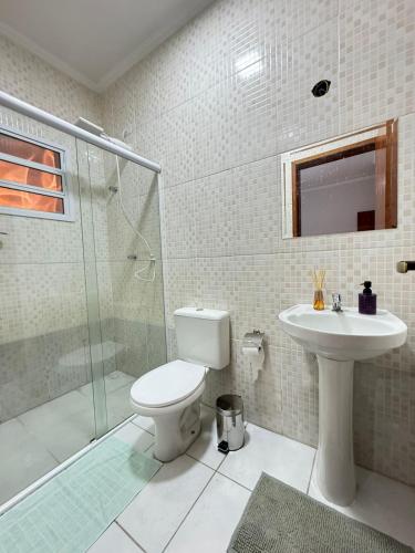 a bathroom with a shower and a toilet and a sink at Casa Carvalho in Peruíbe