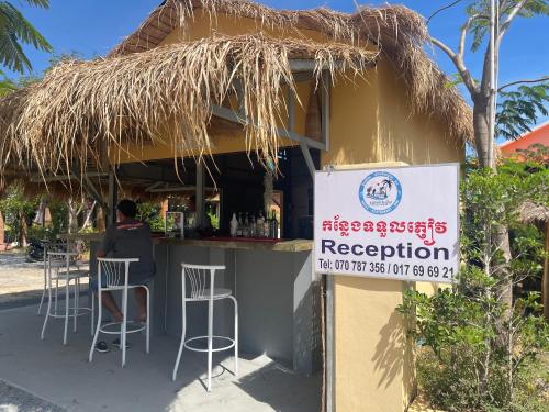a man sitting at a bar in front of a restaurant at The Last Beach House in Kampot
