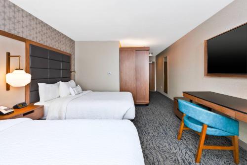 a hotel room with two beds and a desk and a television at Fairfield Inn & Suites by Marriott Kalamazoo in Kalamazoo