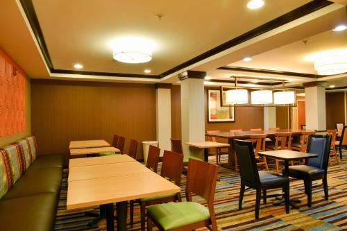 a restaurant with wooden tables and chairs and a couch at Fairfield Inn Hartford Airport in Windsor Locks
