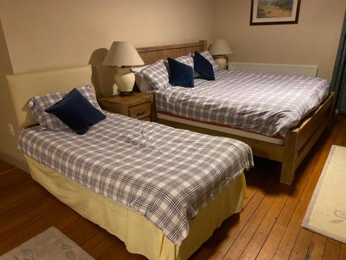 two beds with blue pillows in a hotel room at The Old Flax Mill Yoga Retreat in Coleraine