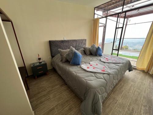 Un dormitorio con una cama y una ventana grande. en MIRADOR CABAÑAS CRISTALES de BELLA VISTA, en Paipa