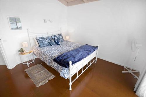 Un dormitorio con una cama blanca con almohadas azules. en A Wood Haven, en Metung