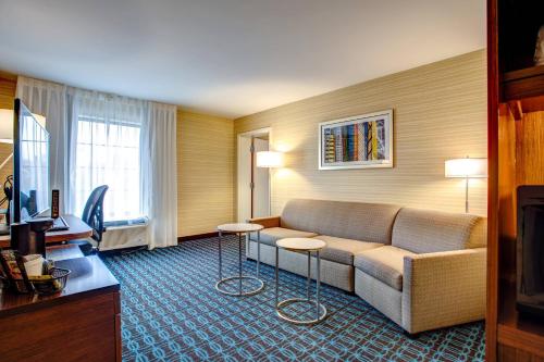 a hotel room with a couch and two tables at Fairfield Inn & Suites by Marriott Springfield Holyoke in Holyoke