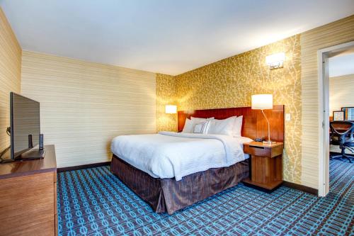 a hotel room with a large bed and a television at Fairfield Inn & Suites by Marriott Springfield Holyoke in Holyoke