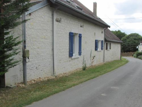 a white building with blue windows on a street at L'autre Monde Chambres D'hôtes in Faverolles
