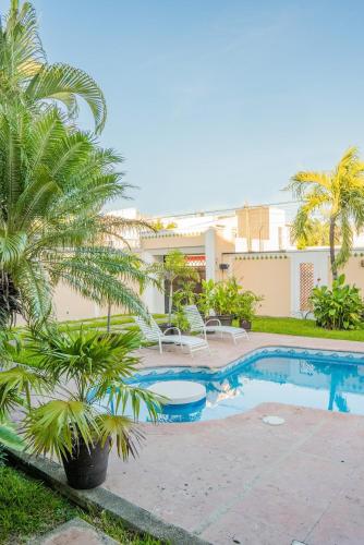 a swimming pool with palm trees in front of a building at Casa privada con alberca grande in Chetumal