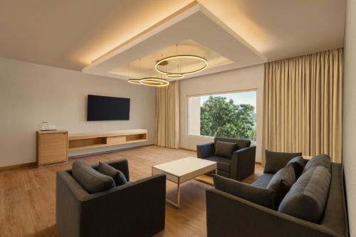 a living room with two couches and a tv at Courtyard by Marriott Tiruchirappalli in Tiruchchirāppalli
