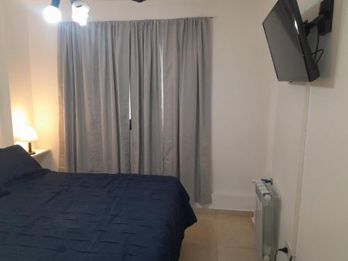 a bedroom with a bed and a tv and a window at Abuela Betty in Villa Carlos Paz