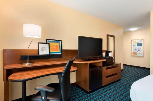 a hotel room with a desk with a computer and a bed at Fairfield Inn & Suites Hartford Manchester in Manchester