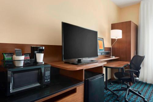 a hotel room with a desk with a television and a microwave at Fairfield Inn & Suites Hartford Manchester in Manchester