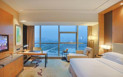 a hotel room with a bed and a desk and a large window at Expo Center Hotel - Free Shuttle Bus & Late Check-out in Yiwu