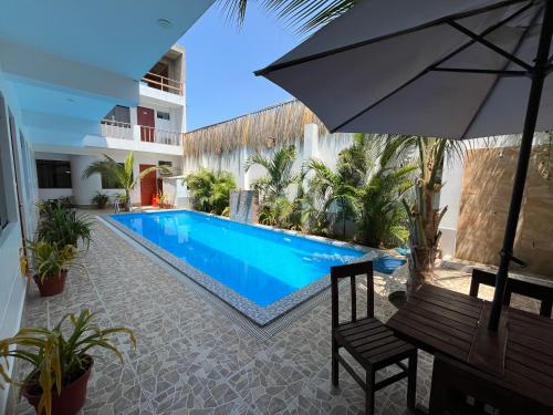 a swimming pool with a bench and an umbrella at Hospedaje Ola Marina in Máncora