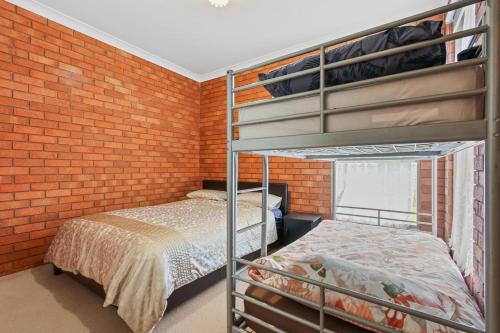 1 dormitorio con litera y pared de ladrillo en Fern Rest, en Lakes Entrance