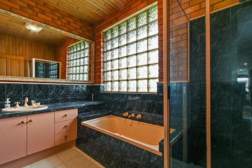 un baño con bañera y lavabo en Fern Rest, en Lakes Entrance