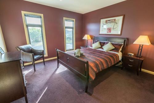 a bedroom with a bed and a chair and two windows at Aqua Vista in Paynesville