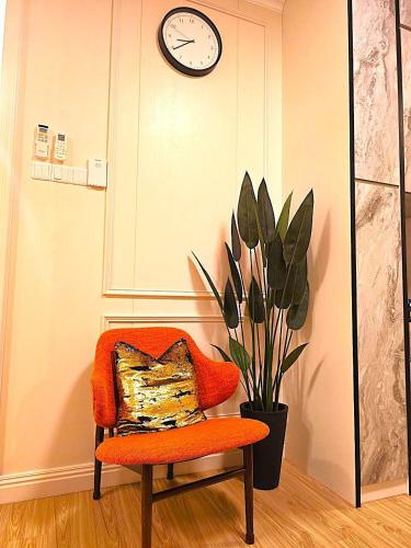 a chair with a pillow and a clock on a wall at Ancozy Desaru Luxury and Comfort Homestay in Bandar Penawar