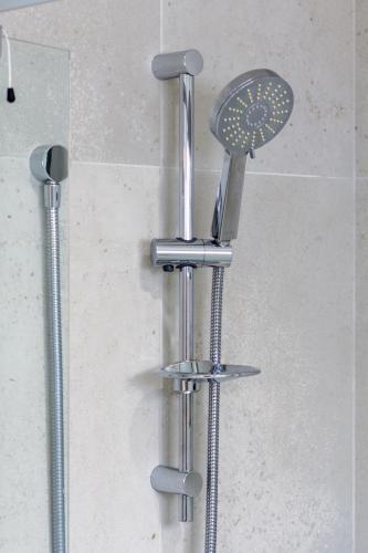 a shower with a shower head on a wall at Beautiful home, Near CBD, Pet Friendly with Carpark in Christchurch