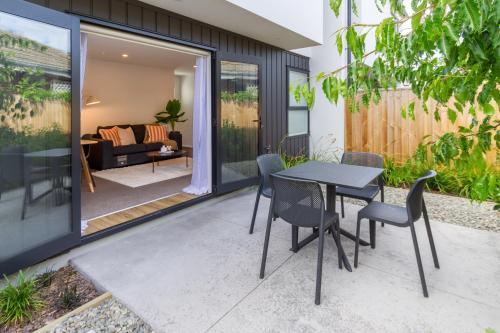 a patio with a table and chairs and a living room at Beautiful home, Near CBD, Pet Friendly with Carpark in Christchurch