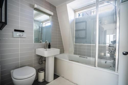 a bathroom with a toilet and a sink and a bath tub at Cosy Home for 6 by Brixton Station in London