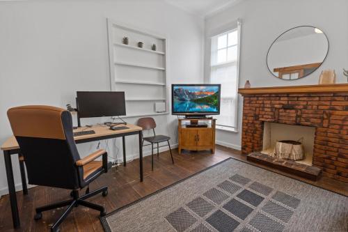 a room with a desk with a computer and a fireplace at Cearc House in Bairnsdale