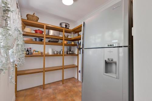 a kitchen with a refrigerator and wooden shelves at Cearc House in Bairnsdale