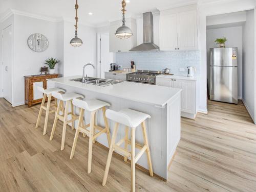 a kitchen with a large white island with bar stools at Banyandah on the Lakes in Paynesville