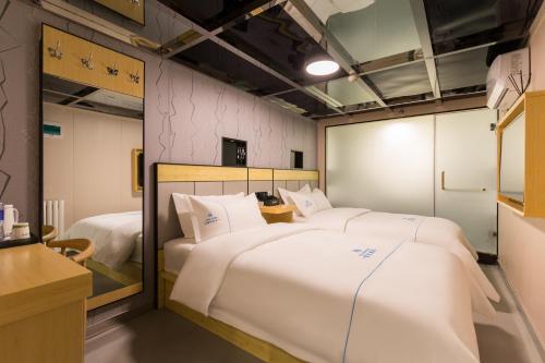 a room with two beds in it at Dequan Hotel Chaoyang Park Branch Coffee fruits, snacks a gym and a laundry room are provided for free in the lobby in Beijing