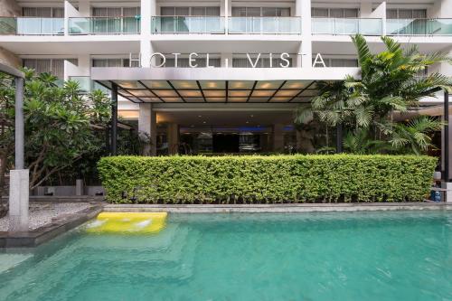 a swimming pool in front of a building at Hotel Vista in Pattaya Central