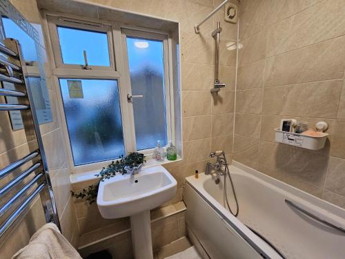 a bathroom with a sink and a tub and a window at London E14 Rooms in London