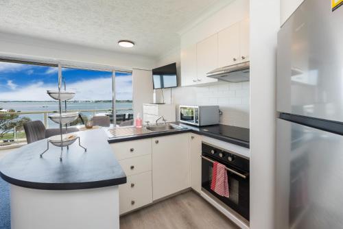 a kitchen with white cabinets and a view of the ocean at Broadwater view in southport 1b in Gold Coast