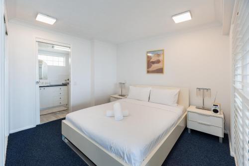 a white bedroom with a white bed with two candles on it at Broadwater view in southport 1b in Gold Coast