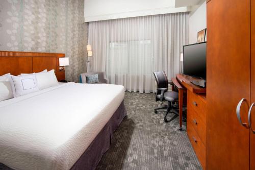 a hotel room with a bed and a flat screen tv at Courtyard by Marriott San Antonio SeaWorld/Lackland in San Antonio