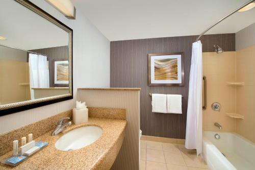 a bathroom with a sink and a tub and a mirror at Courtyard by Marriott San Antonio SeaWorld/Lackland in San Antonio