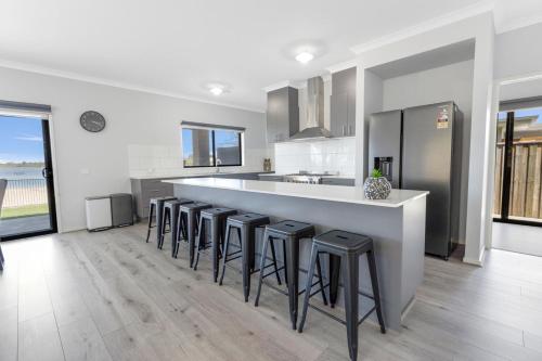 a white kitchen with a bar with stools at Lake Views Retreat in Paynesville