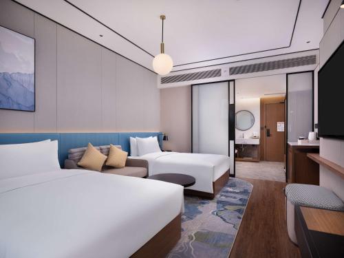 a hotel room with two beds and a couch at Hilton Garden Inn Bazhong Bazhou in Bazhong