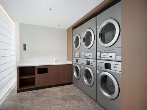 a laundry room with four washing machines and a sink at Hilton Garden Inn Bazhong Bazhou in Bazhong