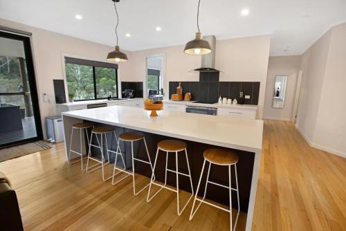 a kitchen with a large white island with bar stools at Rivers Edge in Lake Tyers