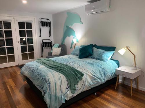 a bedroom with a bed with a blue comforter at Dolphin Cottage in Paynesville