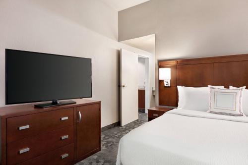 a hotel room with a bed and a flat screen tv at Courtyard by Marriott Tulsa Central in Tulsa