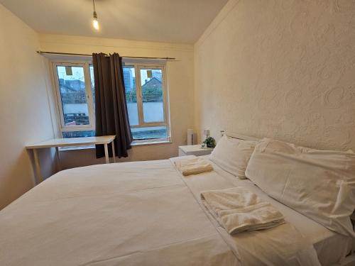 a bedroom with a large white bed with two pillows at London E14 Rooms in London