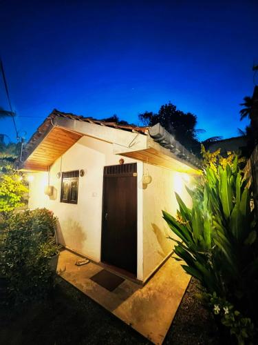a small house with a door in a yard at Moon Bay in Mirissa
