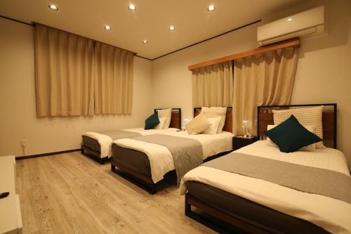 a hotel room with three beds in a room at Nakai House in Tokyo
