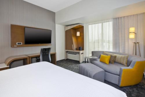 a hotel room with a bed and a couch and a tv at Courtyard by Marriott St. Joseph-Benton Harbor in Benton Harbor