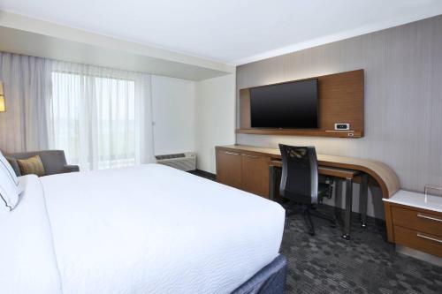 a hotel room with a bed and a desk and a television at Courtyard by Marriott St. Joseph-Benton Harbor in Benton Harbor