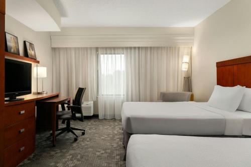 a hotel room with two beds and a desk and a television at Courtyard by Marriott Salisbury in Salisbury