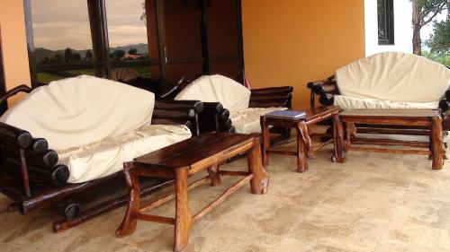 a group of chairs and tables in a room at The Crested Crane Bwindi Hotel in Rugando