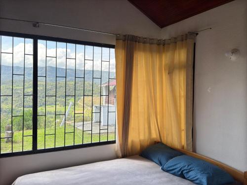 a bed in a room with a large window at Cabaña Campestre San Nicolas in Moniquirá